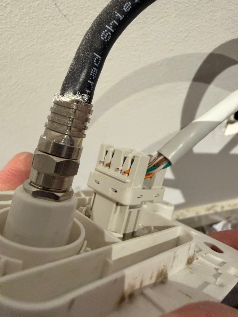 Close-up of Ethernet punch-down wiring behind a wall plate used for home network cabling.