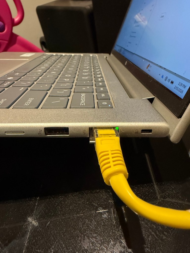 Laptop connected to a wall Ethernet port during troubleshooting of a home internet connection problem.